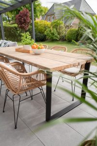 table et chaises en bois posées sur une terrasse carrelée
